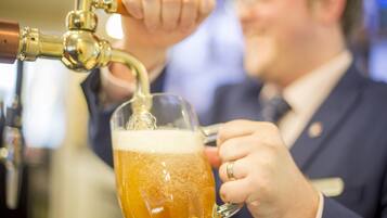 A person pouring beer into a glass mug.