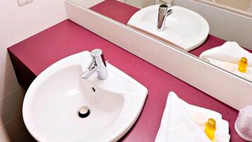 A bathroom with a white sink, a mirror, and a pink countertop.