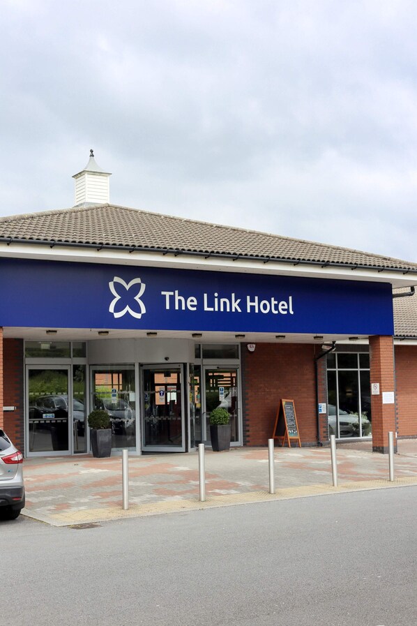 Welcome to The Link Hotel, featuring a modern entrance with large glass doors and a prominent awning.