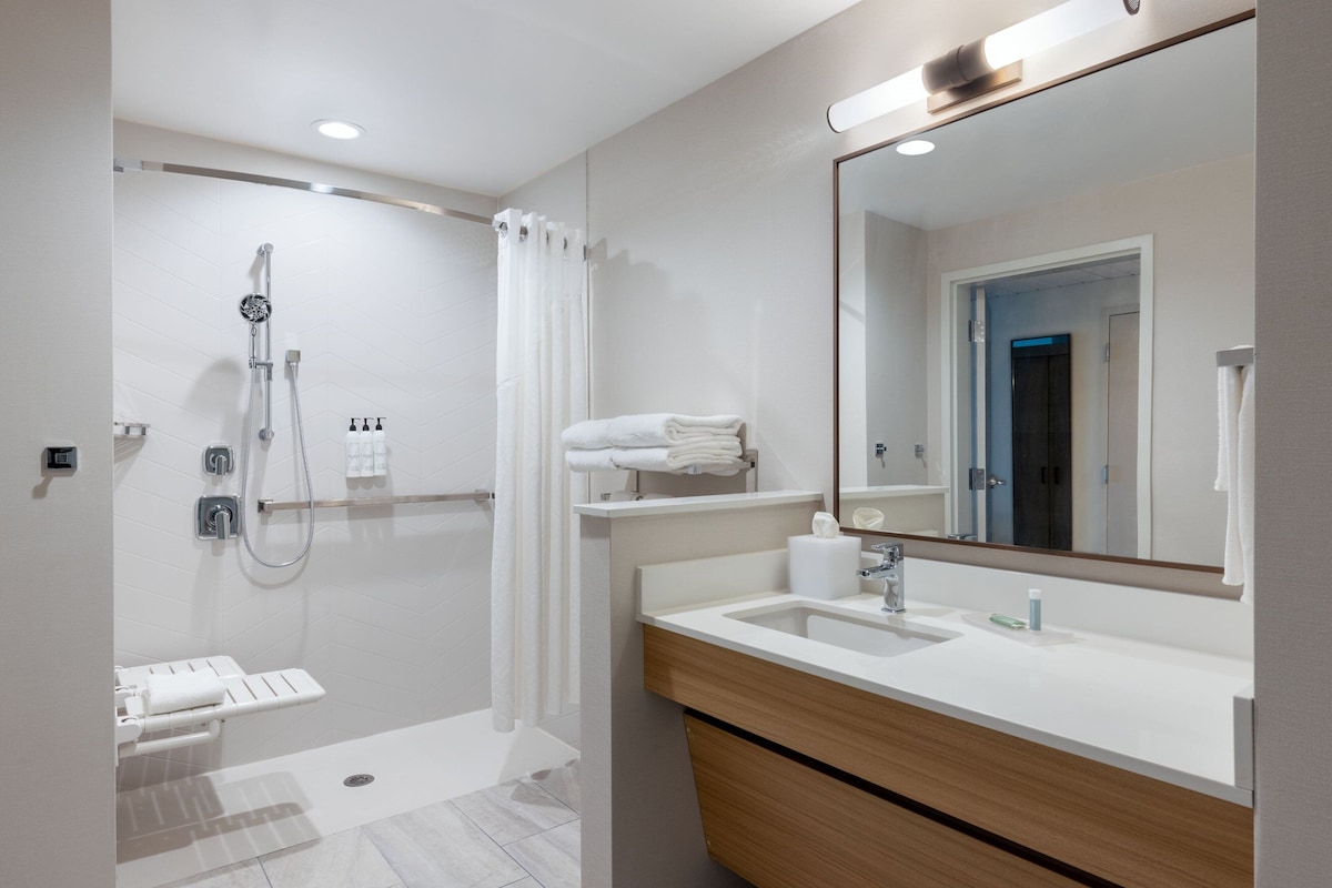 Une salle de bain moderne avec une douche, un lavabo et un miroir.