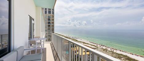 A balcony with a view of the beach and ocean.