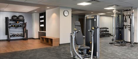 A gym with weightlifting equipment, a wall clock, and a shoe rack.