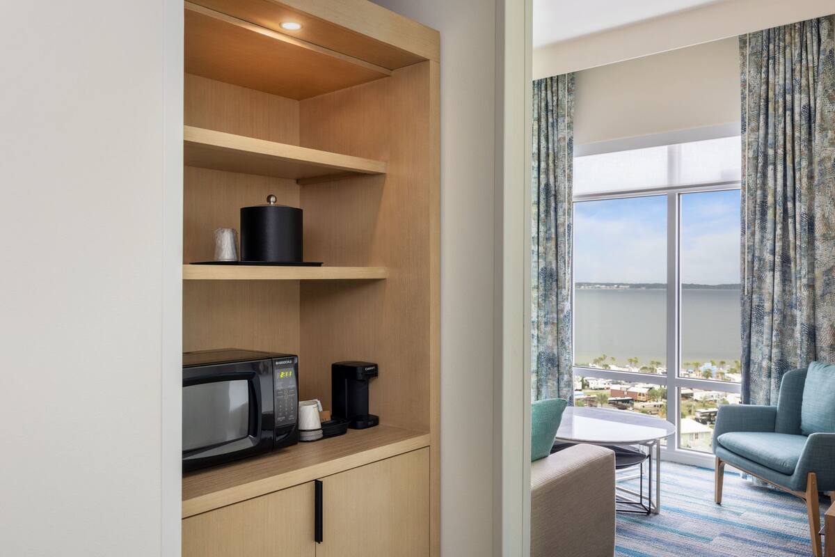 Une chambre d’hôtel dotée d’une kitchenette, d’un coin repas et d’une grande fenêtre offrant une vue dégagée.