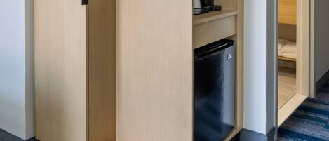 A modern, built-in wardrobe with a microwave and coffee maker on the shelves.