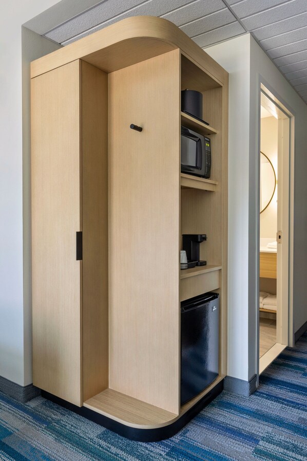 A modern, built-in wardrobe with a microwave and coffee maker on the shelves.
