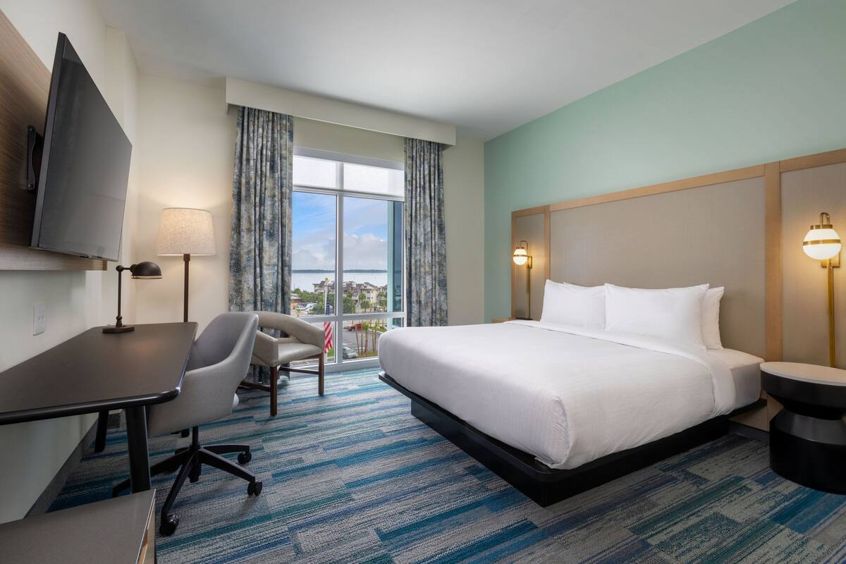 Ein Hotelzimmer mit Bett, Schreibtisch, Stuhl und Fernseher.