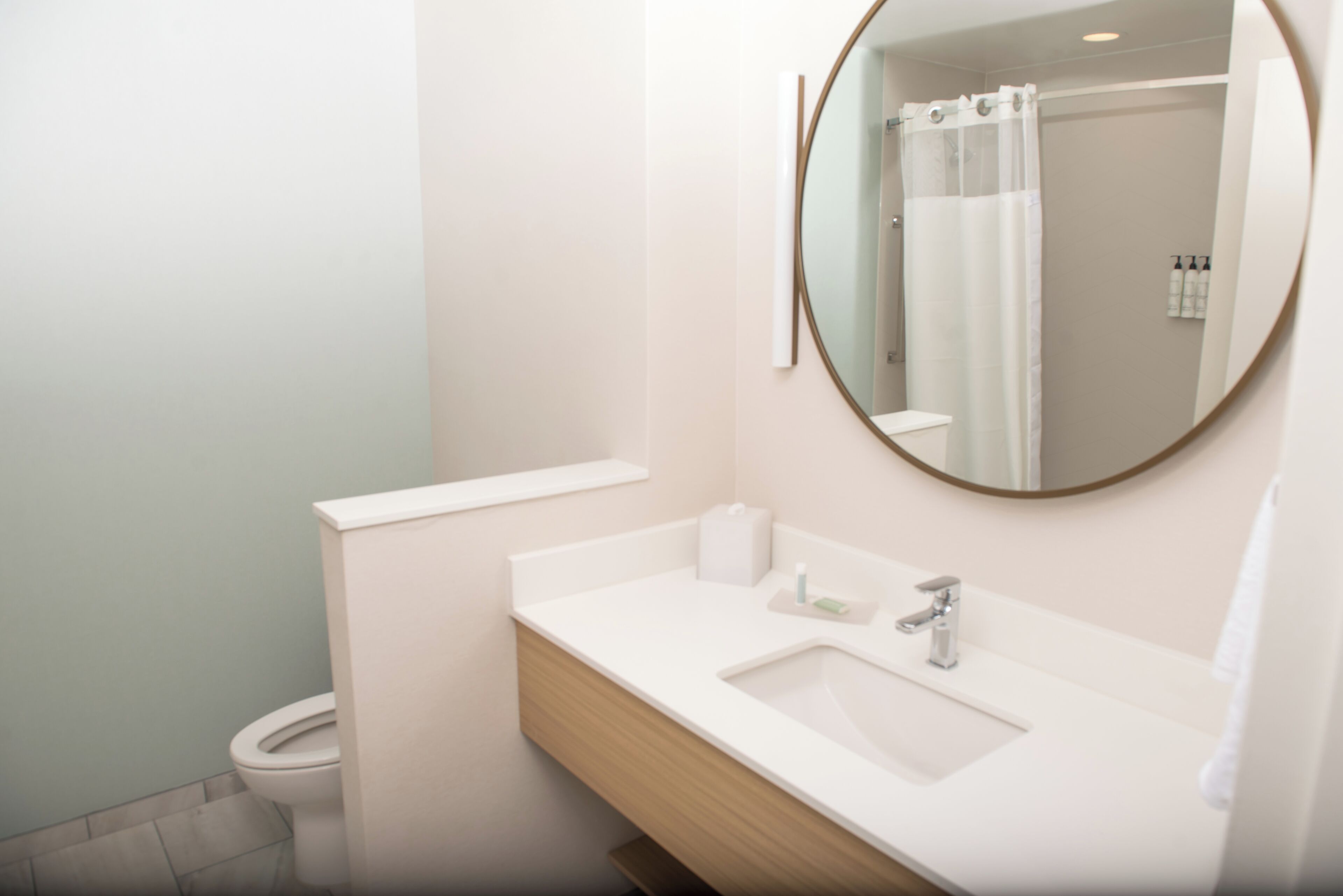 A modern bathroom with a white sink, mirror, and toilet.