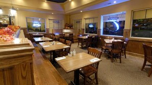 Un restaurante con mesas y sillas de madera, amplios ventanales y vistas de la ciudad.