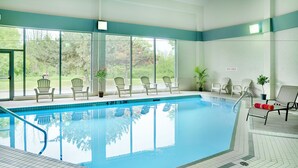 Una piscina interior con paredes de vidrio transparente, múltiples sillas y un letrero que indica 'DEEP AREA'.
