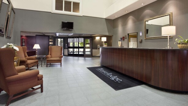 Vestíbulo de hotel con mostrador de recepción, zona de estar y un espejo grande.