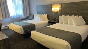 Habitación de hotel con dos camas, un escritorio, una silla, una mesita de noche y una ventana con cortinas.