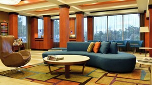A modern lobby with a blue sofa, a round coffee table, and a leather chair. - Fairfield Inn & Suites Hartford Airport (Windsor Locks)
