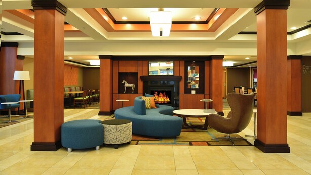 A lobby with a fireplace, seating area, and a reception desk. - Fairfield Inn & Suites Hartford Airport (Windsor Locks)