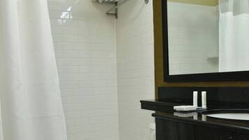 A bathroom with a toilet, a bathtub, a shower curtain, a towel rack, and a mirror.