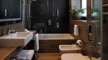 Een moderne badkamer met een grote spiegel, twee wastafels, een bad en een bidet.