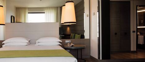 A hotel room with a bed, bedside table, and a view into the bathroom.