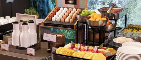 A buffet with various food items including fruits, eggs, and beverages.