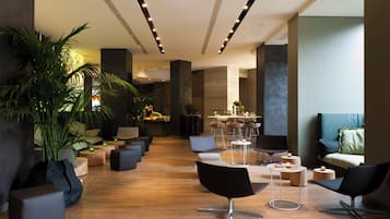 A modern lounge area with seating, a dining area, and potted plants.