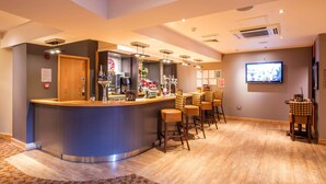 A bar area with a counter, stools, and a television screen. - Premier Inn London Victoria (London)