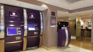 A hotel check-in area with self-service kiosks and a reception desk. - Premier Inn London Victoria (London)