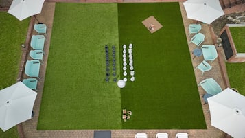 An outdoor patio area with a lawn, chairs, umbrellas, and a brick pathway.