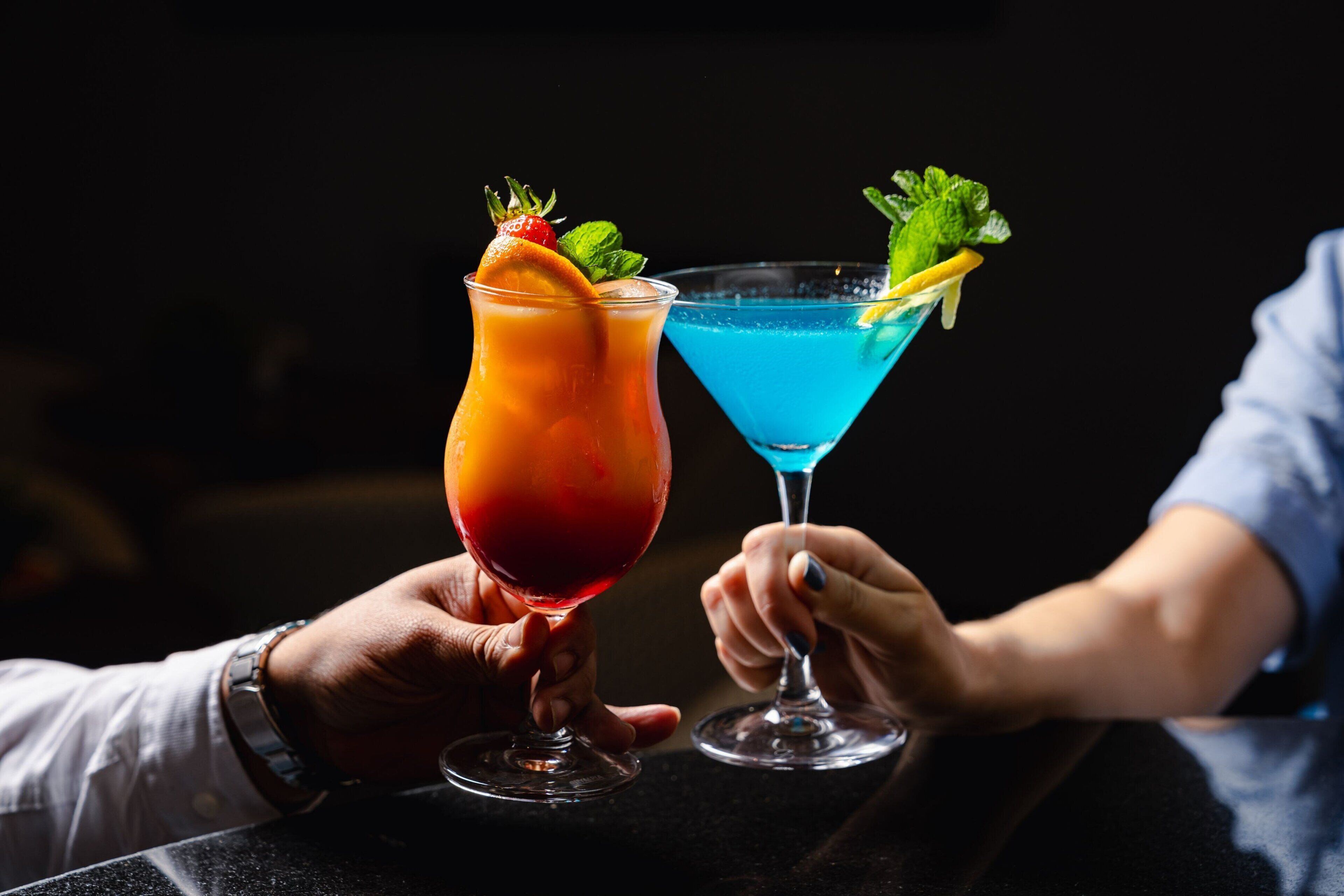 Due persone che sorseggiano cocktail guarniti.