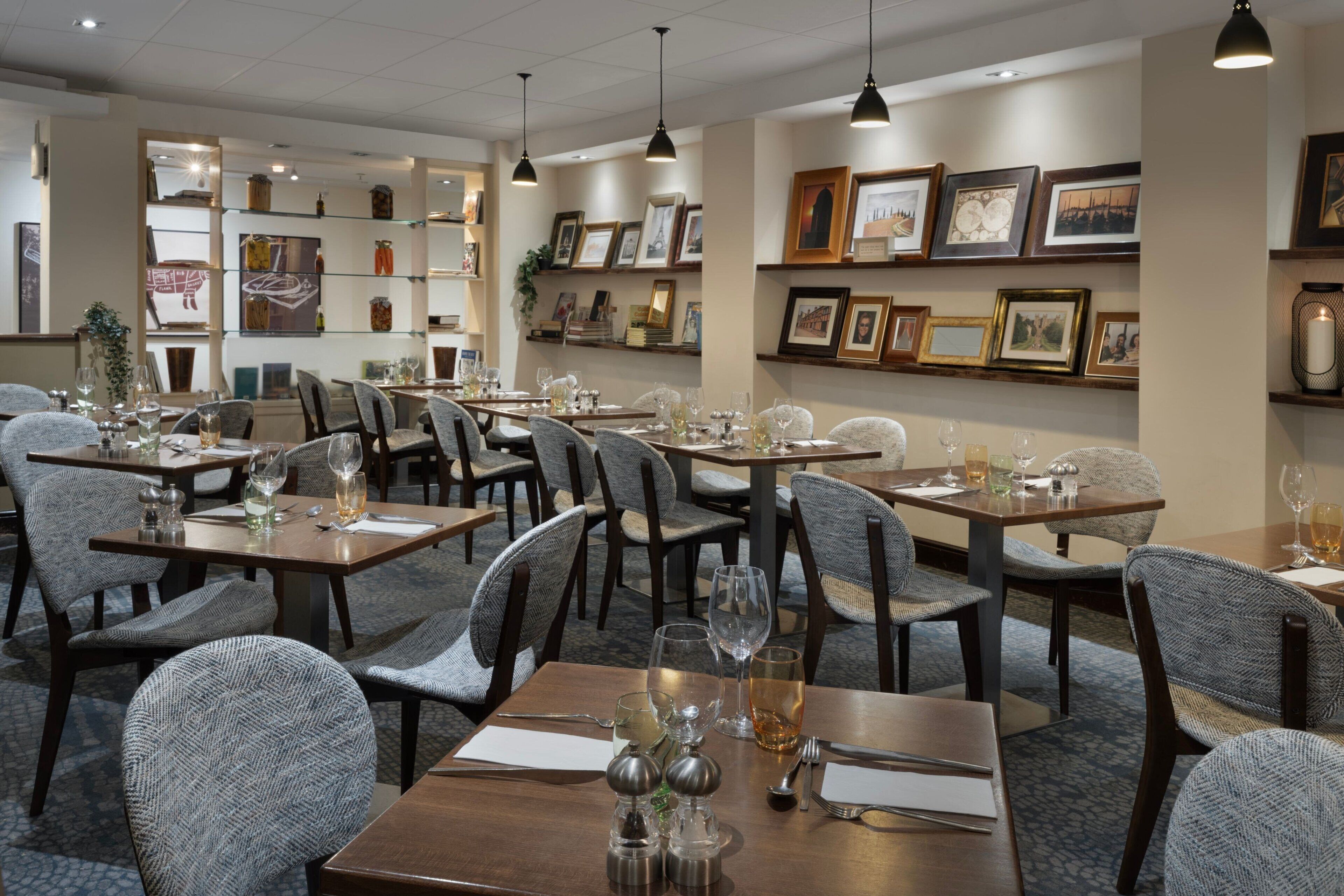 A restaurant with multiple tables and chairs, some with wine glasses and cutlery.