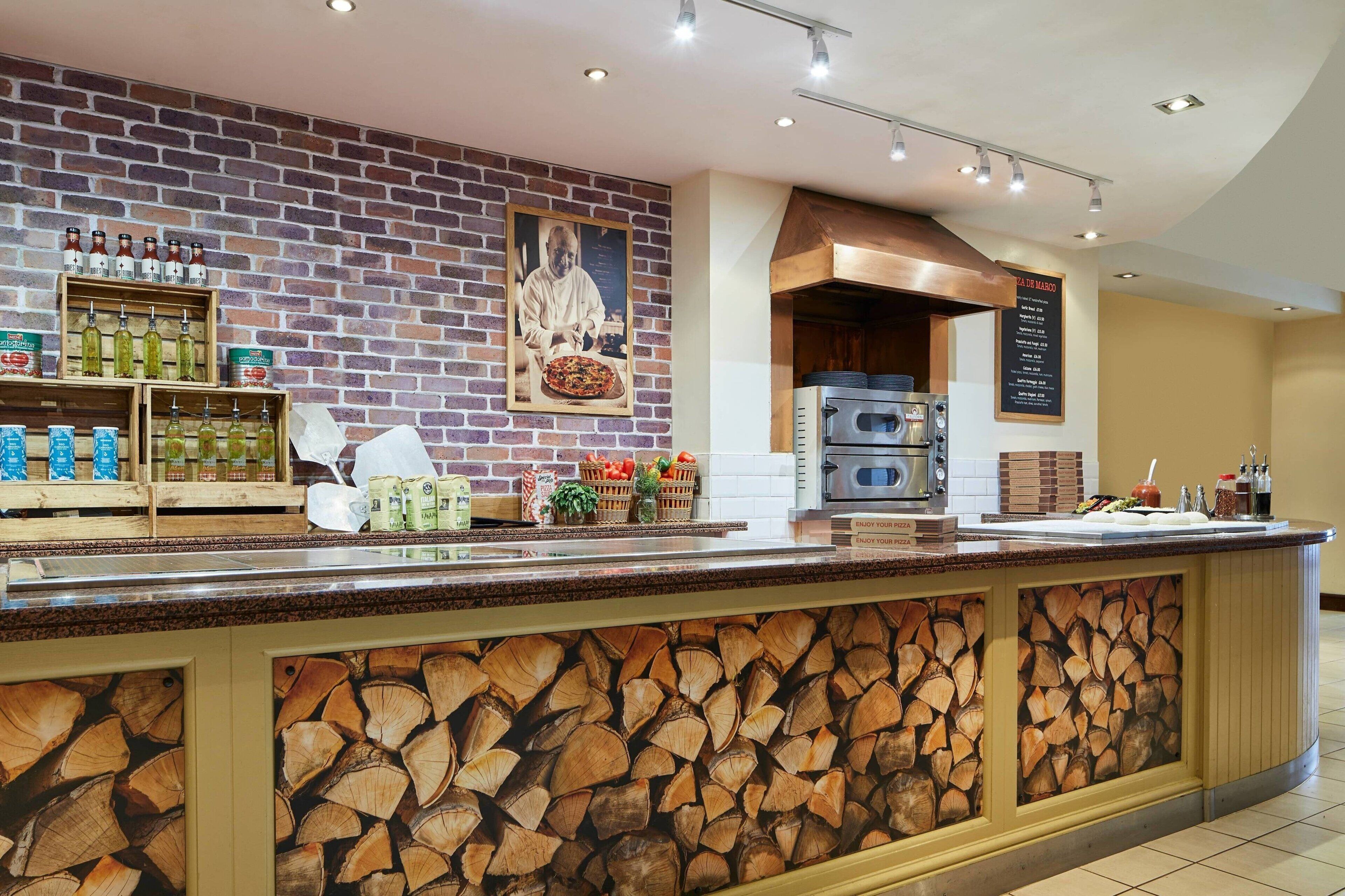 A restaurant with a brick wall, wooden counter, and a menu board.