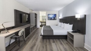 A modern hotel room with a bed, desk, chair, and a TV. - Avanti International Resort (Orlando)