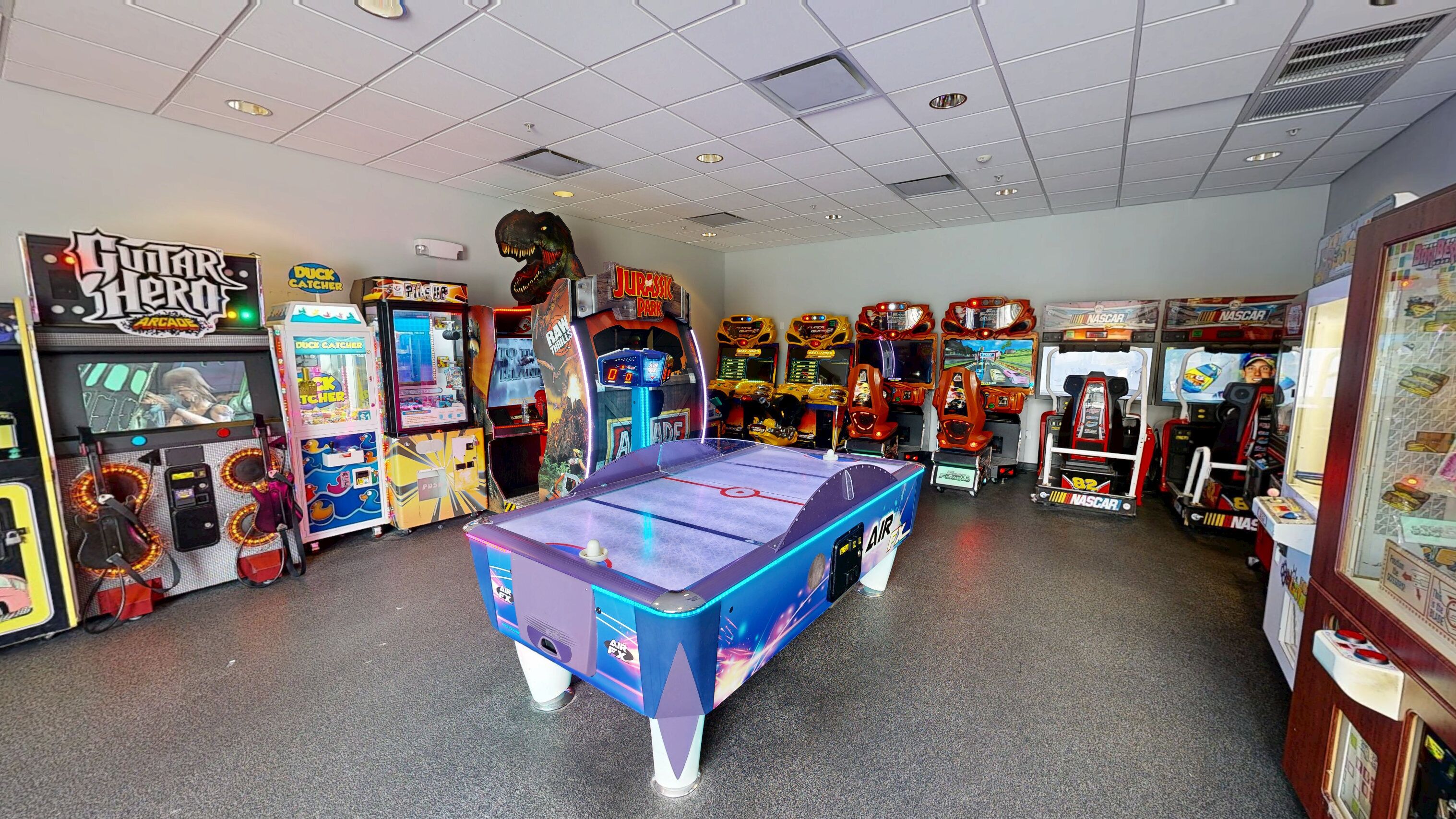 A room with various arcade games, including 'Duck Catcher' and 'Raw Thrills'.