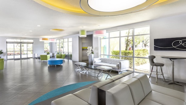 A modern lobby with a seating area, large windows, and a minimalist design. - Avanti International Resort (Orlando)