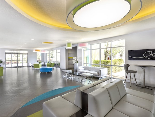 Een moderne lobby met een zithoek, grote ramen en een minimalistisch ontwerp.