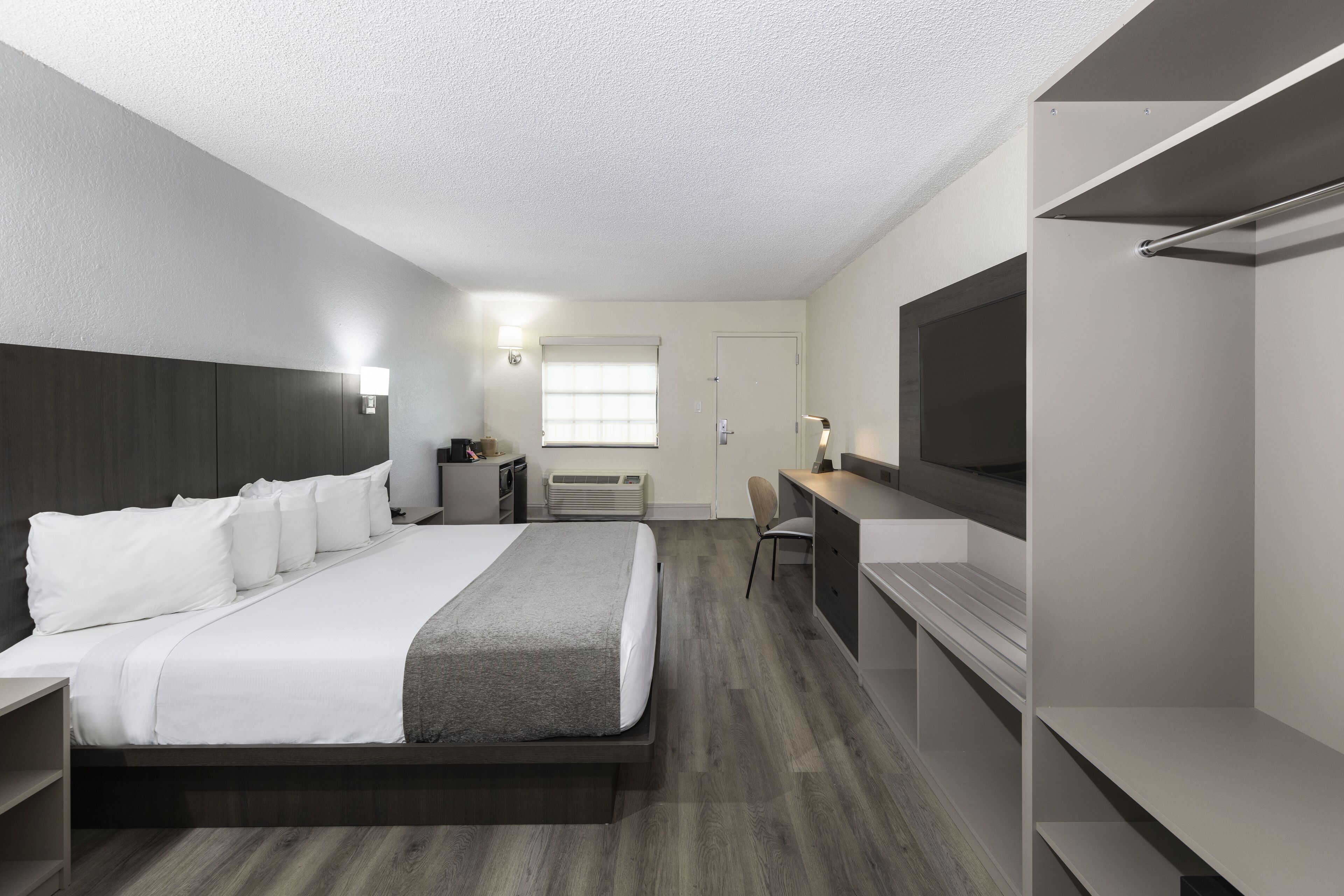 Een moderne hotelkamer met een groot bed, een bureau, een stoel, een televisie en een kledingkast.