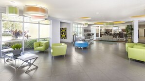 A spacious lobby with modern furniture, large windows, and a visible kitchen area. - Avanti International Resort (Orlando)