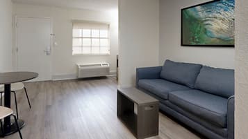 Un salón moderno con un sofá gris, una mesita y una ventana con persianas.