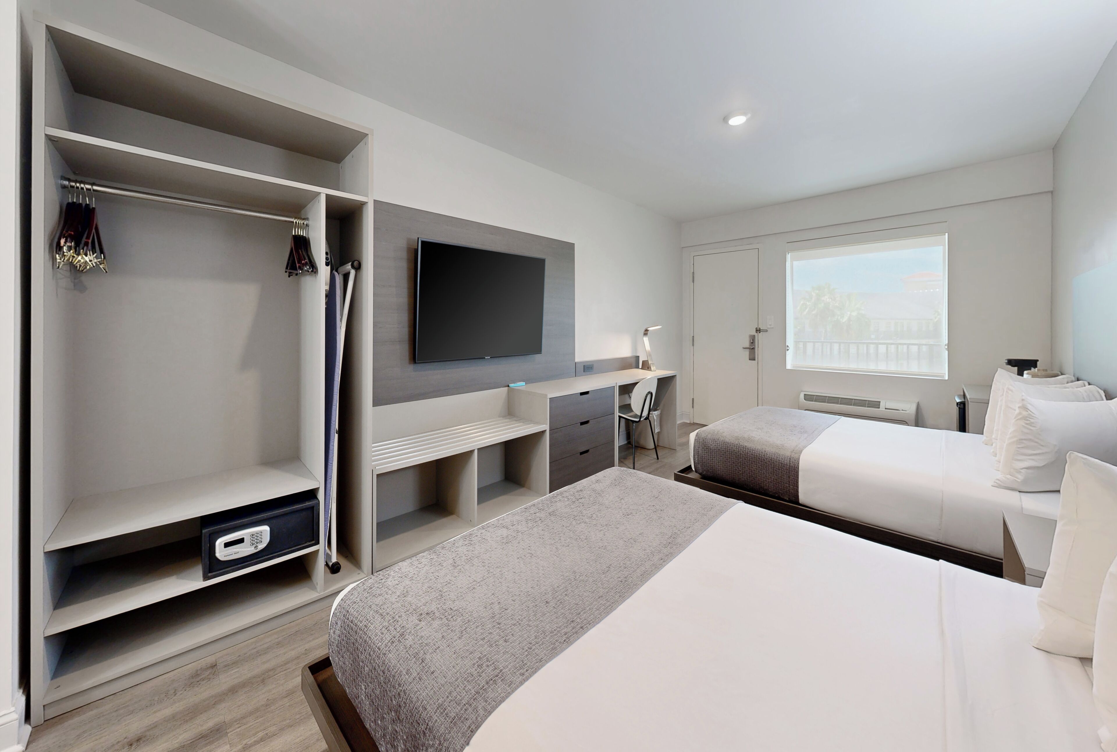 Ein modernes Hotelzimmer mit einem großen Bett, einem Schreibtisch, einem Fernseher und einem Kleiderschrank.