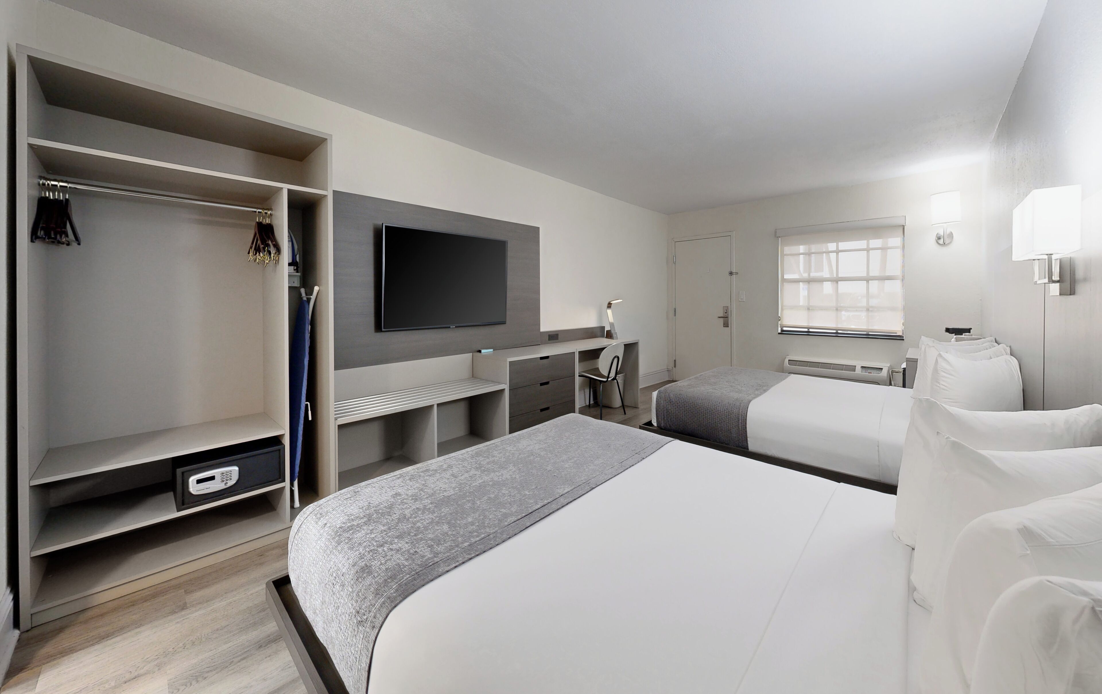 A hotel room with a bed, a desk, a chair, a TV, a wardrobe, and a window.