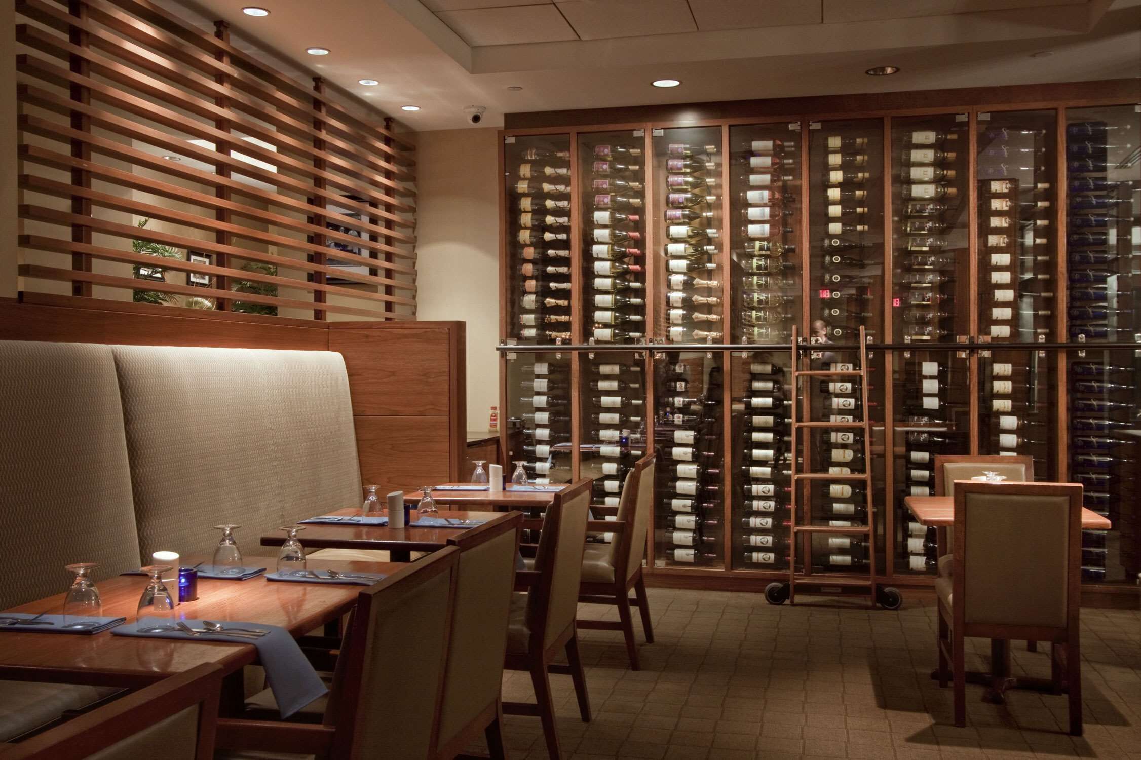 Un restaurante con muebles de madera, una cava de vinos y vistas a la ciudad.