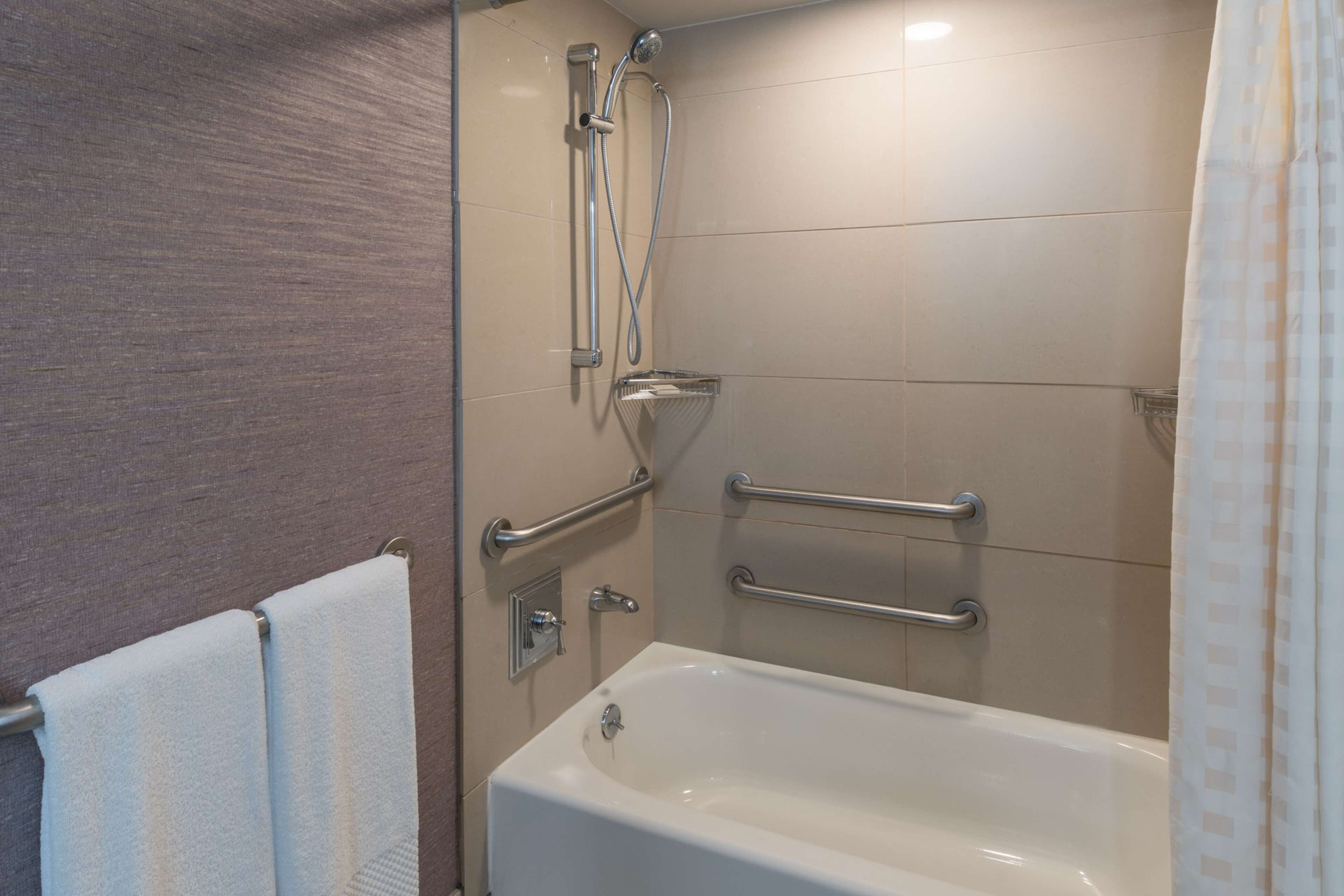 Een moderne badkamer met een bad, grepen en een douchekop.