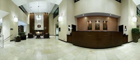 A spacious lobby with a reception desk, seating area, and a fireplace.