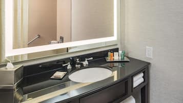 A modern bathroom with a large mirror, black vanity, white sink, and towel storage.