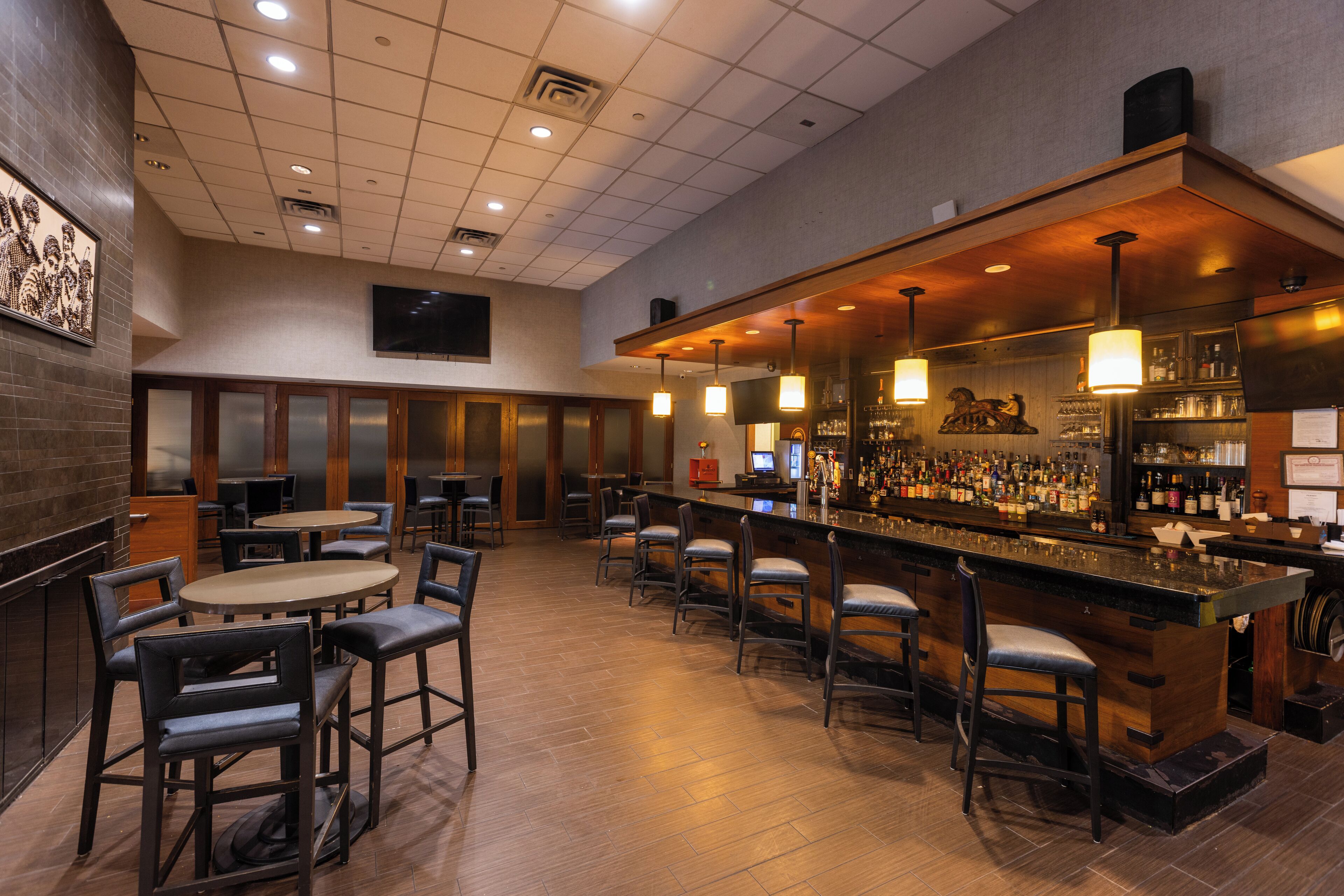A bar area with multiple seating options, a bar counter, and a variety of bottles and glasses.