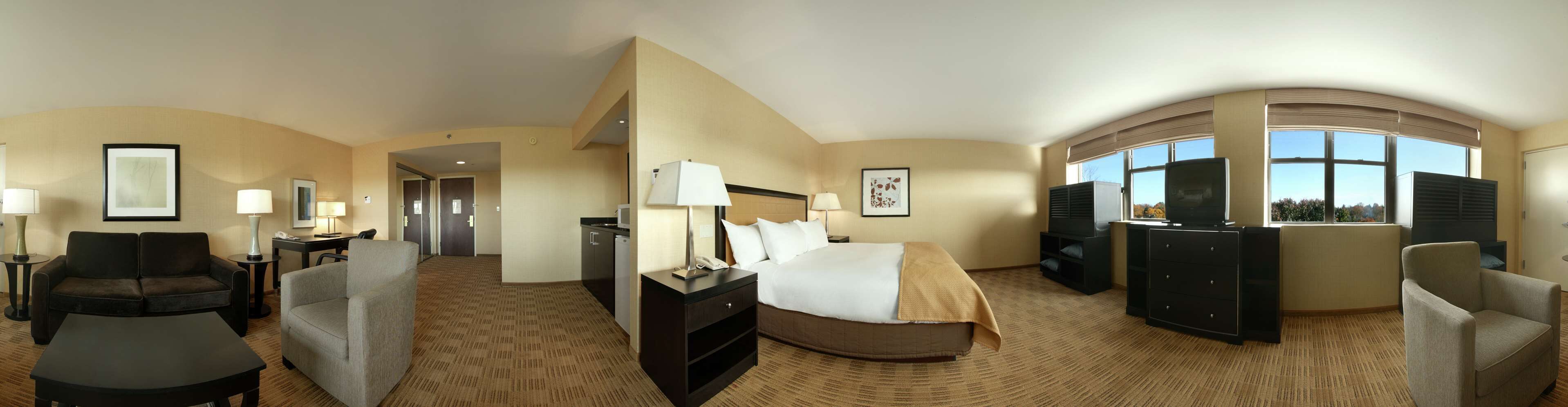 Habitación de hotel con cama, escritorio, silla, sofá y televisor.