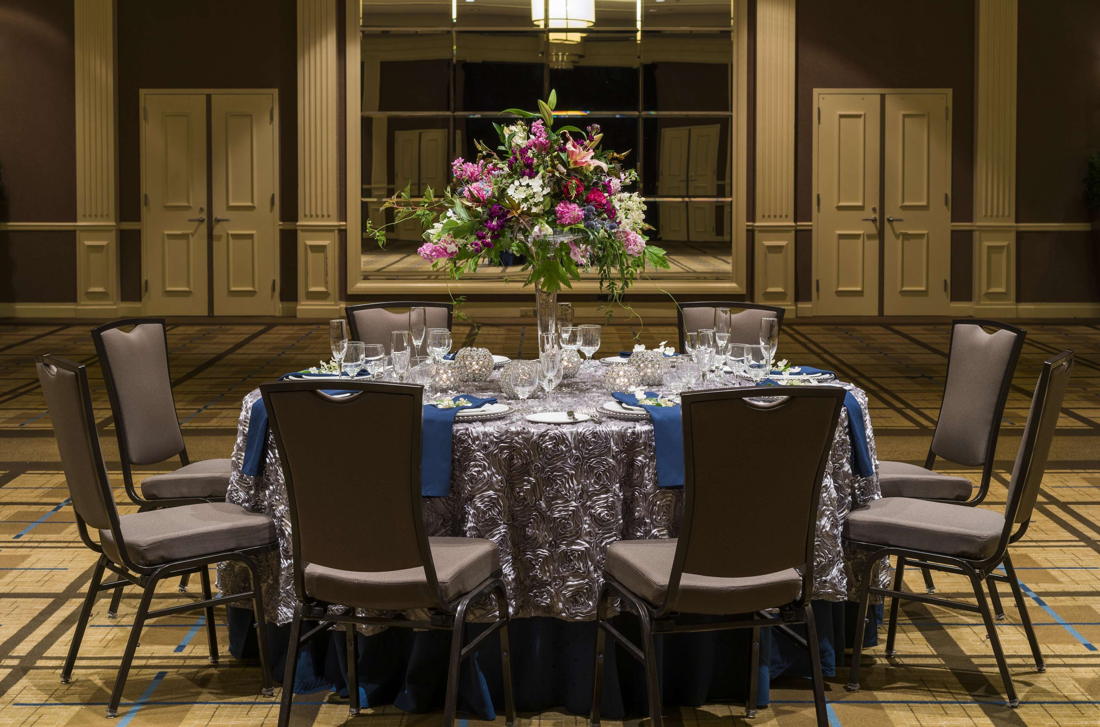 A banquet table set for six with a floral centerpiece, surrounded by six chairs.
