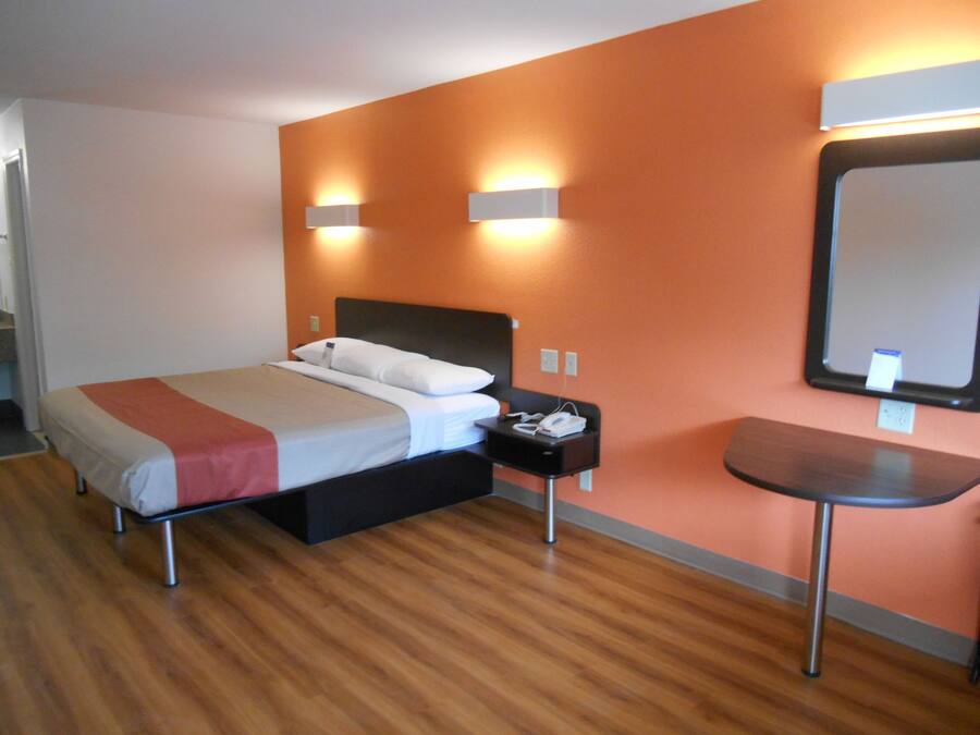Une chambre d’hôtel avec un lit, une table de chevet et un petit bureau avec une chaise.