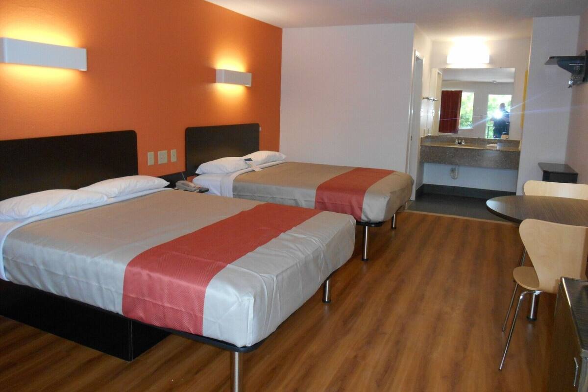 Een hotelkamer met twee bedden, een tafeltje en een spiegel.