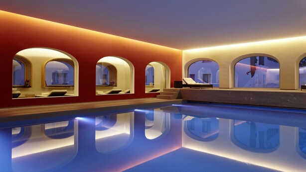 A modern indoor swimming pool with arched windows and a red wall. - Hotel Steffani (St. Moritz)