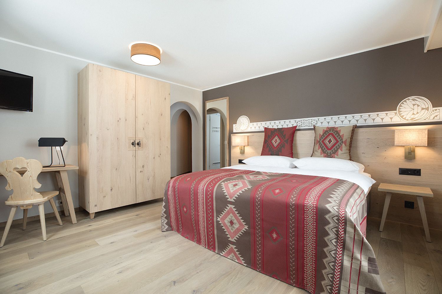 Un dormitorio con cama, armario, escritorio y silla.
