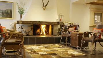 A cozy living room with a fireplace, rustic furniture, and a decorative antler wall piece.