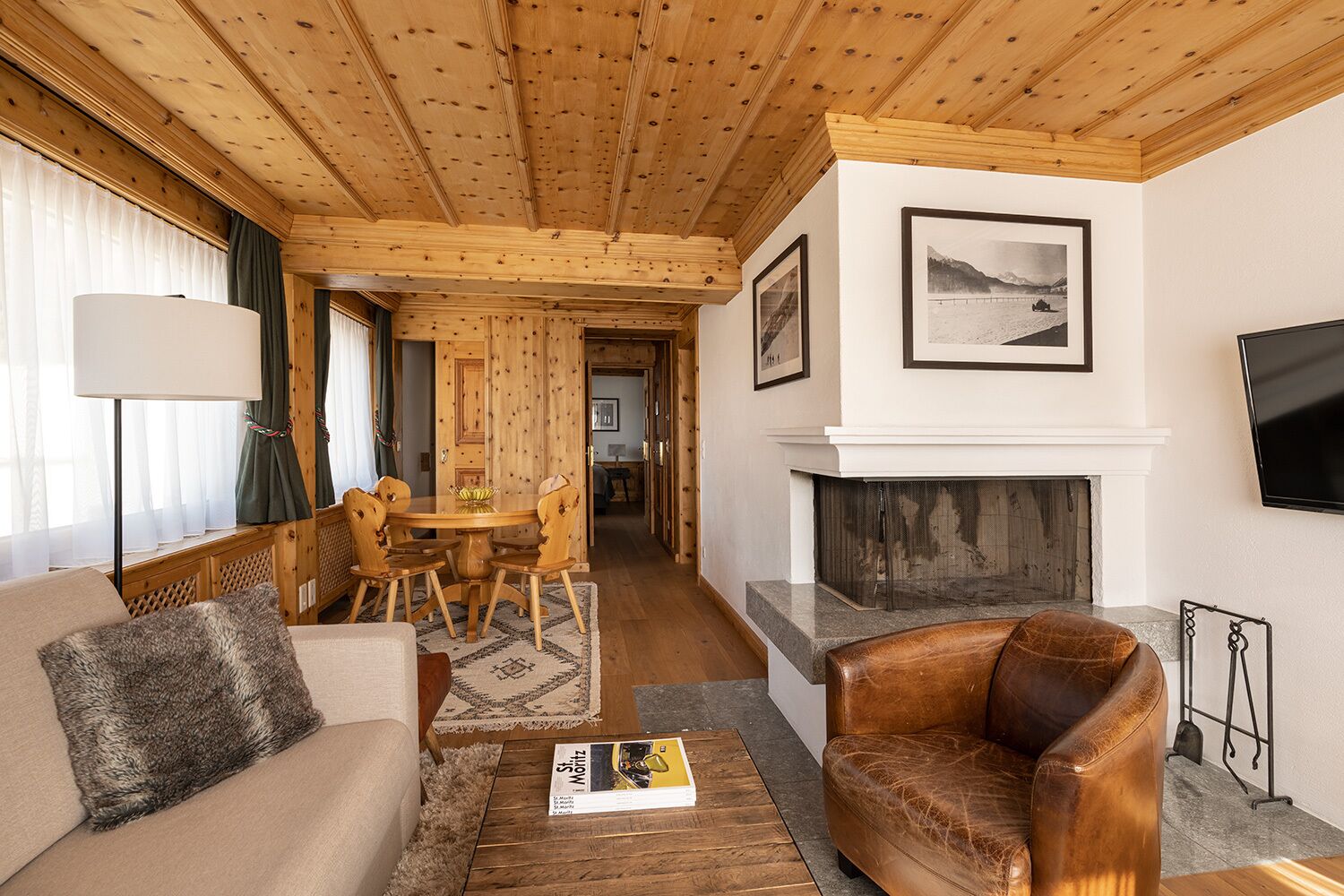 Una sala de estar acogedora con chimenea, techo de madera y un comedor con mesa y sillas.